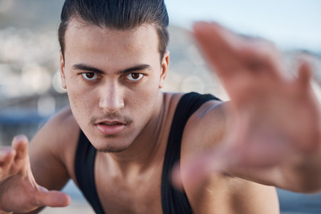 Hands, portrait and a man doing karate in the city, training for taekwondo or sports competition. Serious, fitness and a professional athlete with a move for a workout or martial arts exerciseの写真素材