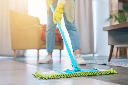 Woman, hands and cleaning floor with mop in living room for hygiene, bacteria or germ removal at home. Female person, housekeeper or maid in domestic service, dirt or dust for disinfection in houseの写真素材