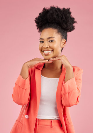 Portrait, fashion and beauty with an afro woman in studio isolated on pink background for trendy style. Smile, hair and face with a happy or confident young african person posing in a clothes outfitの写真素材