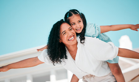 Smile, airplane and mother with her child in the outdoor garden at their family home for adventure. Playful, happy and young mom carrying her girl kid on her back while bonding and playing together.の写真素材