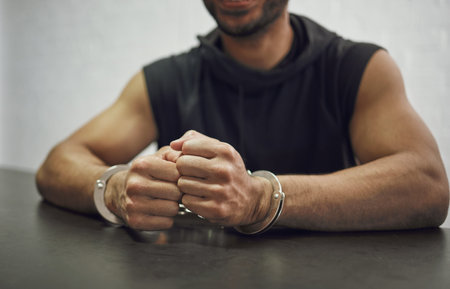Man, criminal and handcuffs for interrogation, crime or money laundering in arrest on table in room....