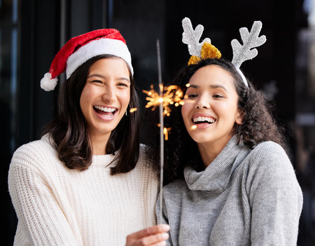 Women friends, Christmas and sparkle stick with smile, home and celebration of festive holiday. Girl, woman and fireworks with light to celebrate for happiness, vacation or laughing with xmas bondingの写真素材