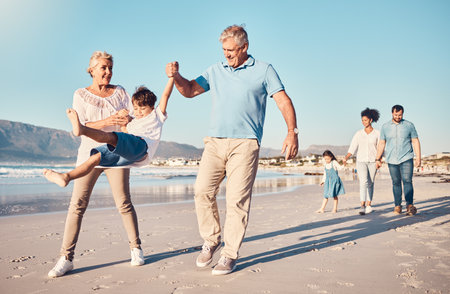 Swinging, grandparents and a child walking on the beach on a family vacation, holiday or adventure in summer. Young boy kid holding hands with a senior man and woman outdoor with fun energy or gameの写真素材