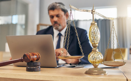 Scales, gavel and man in office with laptop at law firm, online research for court advice and senior...