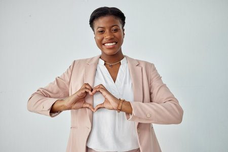 Happy black woman, portrait and heart hands for love, care or compassion against a white studio background. African female person with loving emoji, symbol and sign or hand gesture on mockup spaceの写真素材