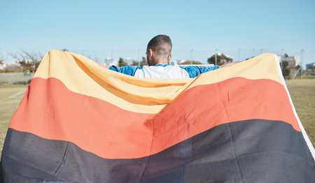 Germany, sports and man with a flag for soccer, motivation and training on a field. Back, fitness and professional athlete or person with representation of a country at a football game or competitionの写真素材