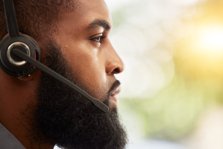 Face, profile of black man and call center, headset with mic and customer service employee, CRM and mockup space. Male consultant at help desk job, flare and serious for contact us and tech supportの写真素材