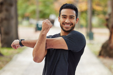 Happy asian man, portrait and stretching arms in fitness getting ready for running, workout or exercise at the park. Male person or runner with smile in warm up arm stretch, training or run in natureの写真素材
