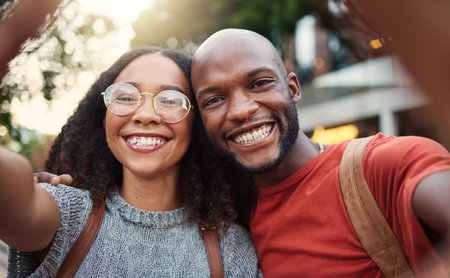 .Selfie, love and smile with an interracial couple in the city together for travel, tourism or adventure overseas. Portrait, freedom or fun with a man and woman taking a photograph in an urban town.の写真素材