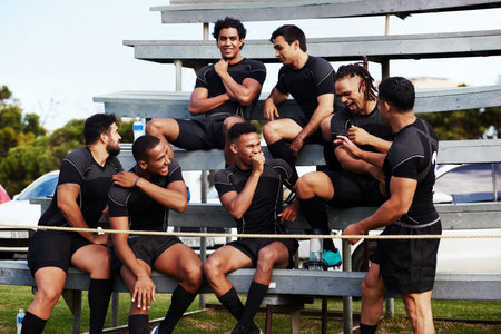 Action isnt just reserved for the field. Shot of a group of young men sitting on the benches together at a rugby game.の写真素材