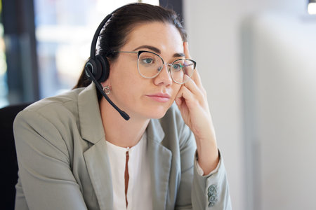 Customer service, computer and business woman bored with help desk work, networking overtime or telemarketing. Burnout fatigue, technical support and insurance agent tired, depressed and reading infoの写真素材
