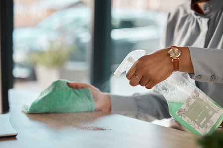 Hands, cleaning and product on a wooden table for hygiene, disinfection or to sanitize a surface in a home. Gloves, bacteria and spray with a woman cleaner in the living room for housework or choresの写真素材