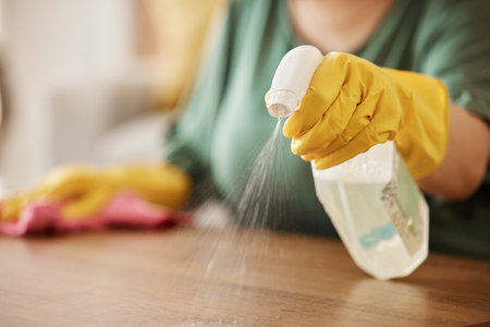 Hand, spray bottle and a woman cleaning a wooden surface in her home for hygiene or disinfection. Gloves, product and bacteria with a female cleaner using detergent to spring clean in an apartmentの写真素材