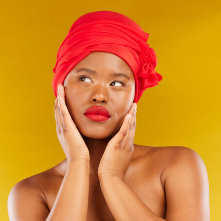 Face makeup, red lipstick and black woman with natural skincare shine, real aesthetic beauty or anti aging. Studio cosmetics, head scarf and African person touch smooth skin on yellow backgroundの写真素材