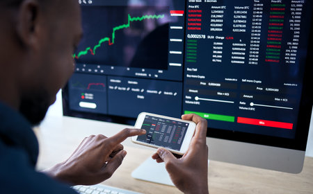 Phone, computer and corporate man with stock market statistics, NFT insight or investment data of IPO fintech company. Crypto trading, economy and African male trader reading finance accounting infoの写真素材