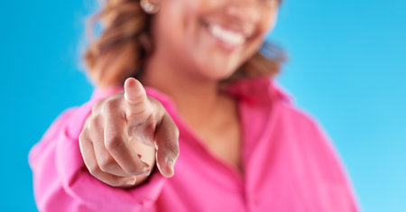 Pointing, finger choice and a woman on a blue background for recruitment, hiring and motivation. Smile, offer and hand of a person or girl with a decision isolated on a studio backdrop for promoの写真素材
