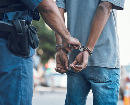Handcuffs, police and hands of police man with criminal in city for justice, crime or corruption. Illegal, arrest and law enforcement officer with suspect, thief or gangster for jail, robbery or failの写真素材
