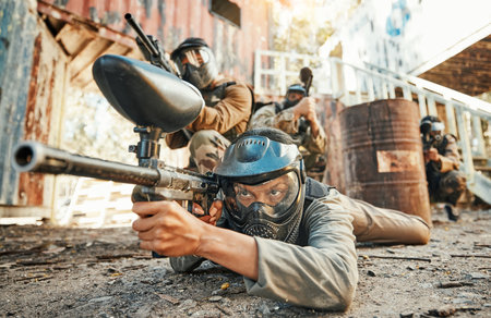 Paintball, team and people in action with gun for tournament, competition and battle in nature. Sports, military and men on ground shooting in outdoor arena for training, adventure games or challengeの写真素材