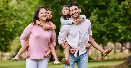 Portrait, piggyback and happy asian family in a park with love, smile and games in nature. Face, freedom and parents carrying children in a forest, bonding and playing together on the weekend outdoorの写真素材