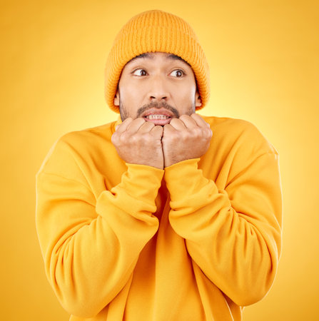 Surprise, face and asian male shocked by winter, fashion and sale announcement in studio on yellow background. Wtf, worry and Japanese male customer with omg deal, news or coming soon promotionの写真素材