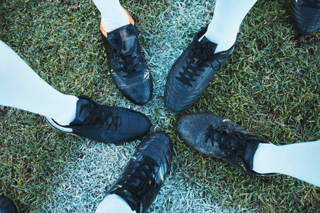 Soccer, sport shoes and teamwork with people together on a grass field for motivation or competition. Closeup, above and football player or athlete group on a pitch for training, exercise or fitnessの写真素材