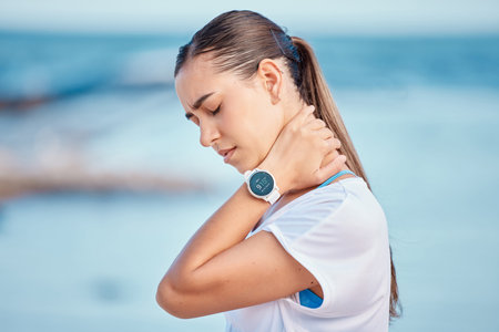Outdoor, woman and shoulder or neck pain from exercise at the beach, ocean or workout to relax...