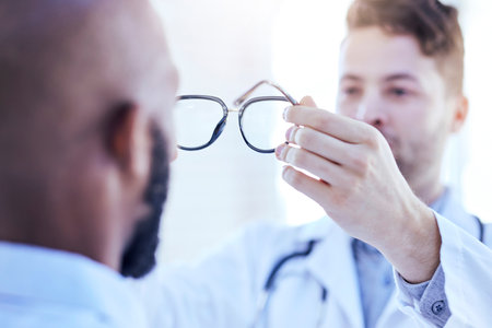 Hands, man and optometrist with glasses for eye support and lens check at a doctor consultation. Medical, wellness and back of patient with vision and eyewear care with professional holding frameの写真素材