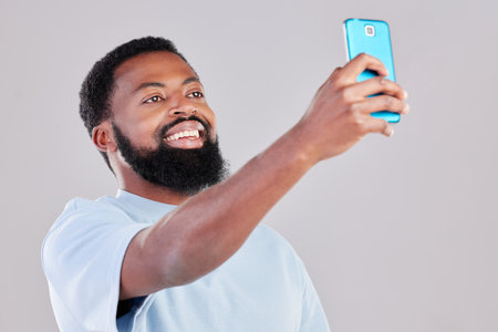 Happy black man, selfie and photography for social media, vlog or networking against a grey studio background. African male person smile for photo, memory or online communication and picture postの写真素材