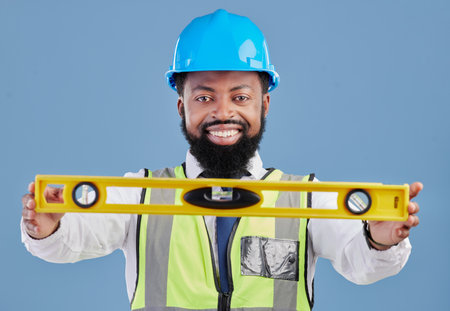 Happy black man, portrait and architect with level for measuring in construction against a blue studio background. African male person, engineer or contractor smile holding tool for measurementsの写真素材