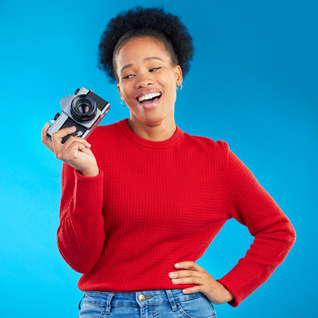Photographer woman, thinking and camera in studio for photoshoot, memory and magazine by blue background. Young journalist girl, retro tech and lens for paparazzi, newspaper or content creator jobの写真素材
