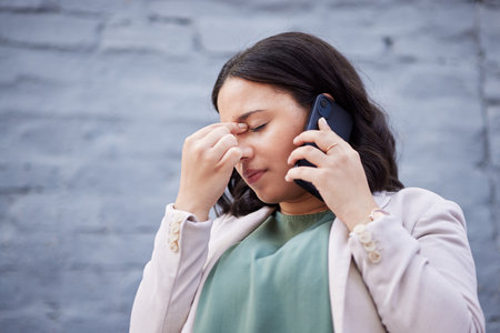 Headache, phone call and business woman in city with bad news and stress from work. Burnout, urban and female professional frustrated from job fail with anxiety and mobile networking in conversationの写真素材