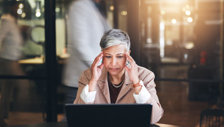 Stress, headache and laptop with business woman in office for fatigue, anxiety and report. Mental health, burnout and frustrated with senior employee and blur for glitch, confused and project problemの写真素材