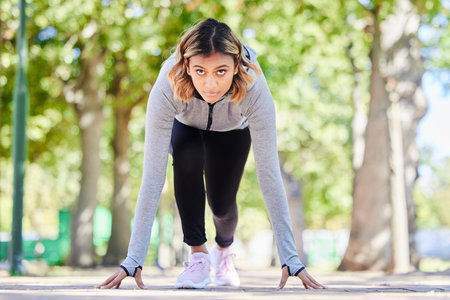 Run, exercise and a woman in start position outdoor at a park with commitment and focus on wellness....