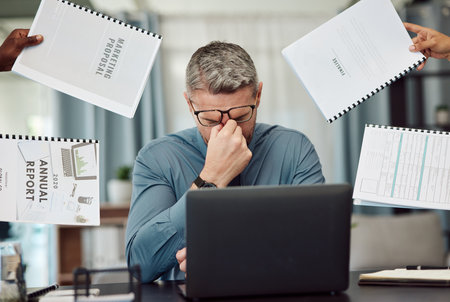 Business man, stress and overwhelmed with headache, documents and staff hands in busy office. CEO, manager or tired boss with laptop, paperwork and burnout with employee group at marketing agencyの写真素材