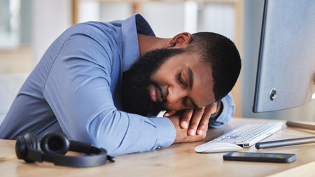 Call center, tired business man and sleeping at desk with burnout, fatigue and low energy in telemarketing office. Lazy, depressed and stress of african sales consultant taking a nap in CRM agencyの写真素材