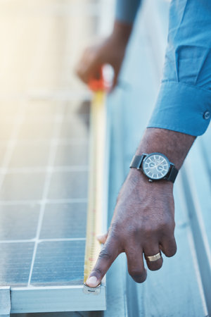 Engineer, hands and tape to measure solar panel on rooftop for sustainable planning, construction and building grid. Closeup of technician, electrician and man with measurement of photovoltaic systemの写真素材