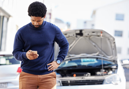 Black man with phone, car breakdown and typing in road with contact, auto insurance and travel....