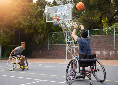 Sports, basketball and men in wheelchair for goal in training, exercise and workout on outdoor court. Fitness, team and male people with a disability shoot ball for competition, practice and gamesの写真素材