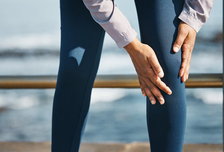 Knee pain, hands and injury, fitness outdoor and person with medical emergency and inflammation. Muscle tension, osteoporosis or fibromyalgia with health, legs and exercise with running in natureの写真素材