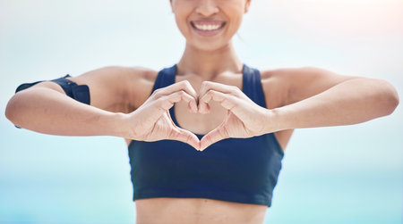Heart, hands and fitness of sports woman outdoor for freedom, wellness and healthy review. Closeup of happy athlete show finger shape for love, support and motivation for care, emoji sign and iconの写真素材