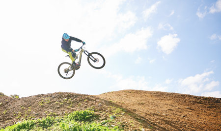 Mountain bike, man and jump in sky for competition, freedom and off road adventure. Athlete, extreme sports and bicycle in air for action, cardio race and stunt power in nature, path and mockup spaceの写真素材