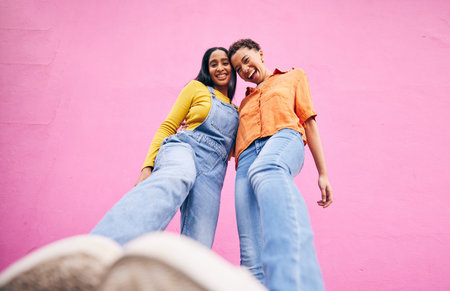Selfie, fashion and portrait of friends on pink background in city with trendy clothes, stylish and cool outfit. Happy, creative and below of female people for freedom on holiday, vacation or weekendの写真素材