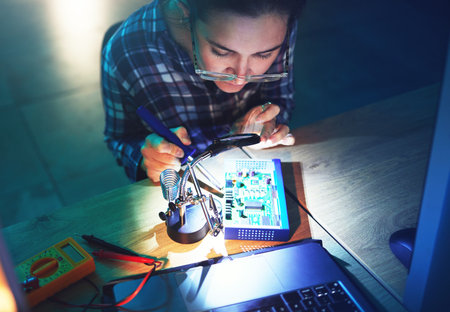 Woman, technician and motherboard with microchip, electronics or soldering iron in top view at laboratory. Information technology, circuit board or programming for future, hardware and system upgradeの写真素材