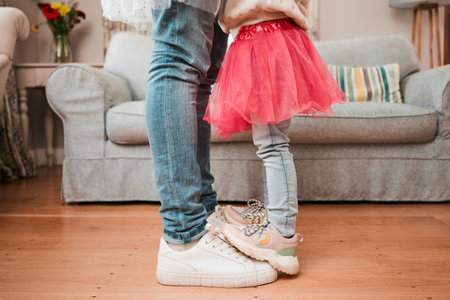 Dance, feet and home with father and daughter in living room for ballet, princess and love. Music, care and learning with closeup of man and child in family house for helping, youth and energyの写真素材