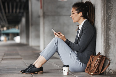 Woman, reading and phone on coffee break in the city, street or employee relax on social media, internet or online job search. Unemployment, news and worker sitting to check email on cellphoneの写真素材