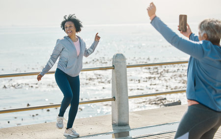Phone, friends picture and senior woman smile at beach with silly pose at sea for fitness. Exercise,...