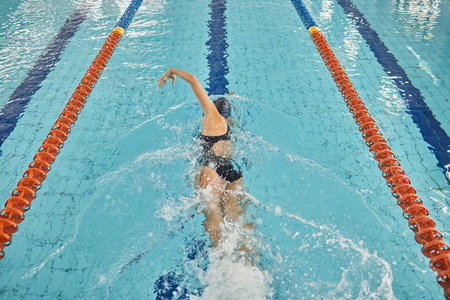 Person, freestyle and swimming in pool for sports competition, challenge and fitness training. Athlete, woman and swimmer in workout exercise for water race stroke, speed and triathlon championshipの写真素材