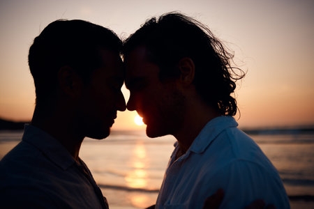 Beach, sunset and gay couple in silhouette, embrace and love on summer island vacation together in...