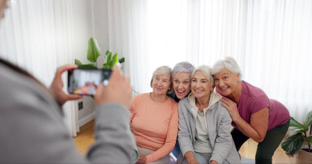 Senior fitness, women and person with a photo for a yoga, exercise or workout memory together. Smile, group and coach taking picture of elderly friends at a training studio for a class in retirementの写真素材