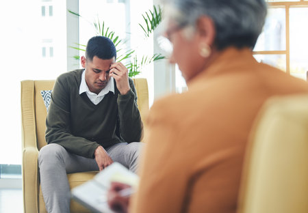 Psychologist notes, man stress and sofa with woman, therapy or listen for mental health, mindset or care. Psychiatrist, patient and frustrated in clinic, book or couch for help, anxiety or depressionの写真素材